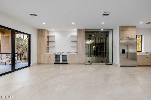 bar featuring light brown cabinets, stainless steel built in refrigerator, and beverage cooler