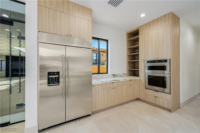 kitchen with light brown cabinetry and appliances with stainless steel finishes