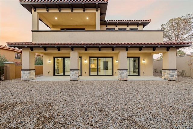 back house at dusk with a patio area and a balcony