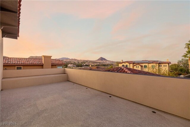 patio terrace at dusk with a mountain view and a balcony