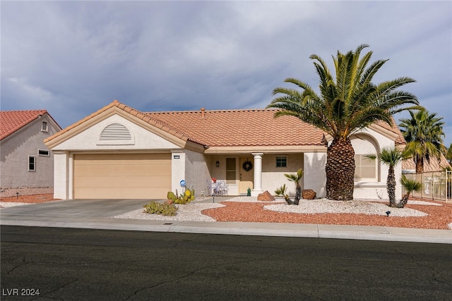 view of front facade with a garage, a tiled roof, concrete driveway, and stucco siding