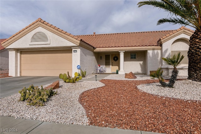 mediterranean / spanish house with concrete driveway, a tile roof, an attached garage, and stucco siding