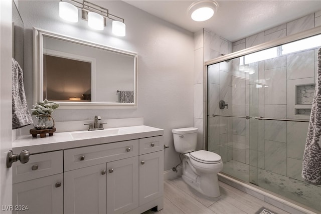 full bathroom featuring toilet, a shower stall, baseboards, and vanity