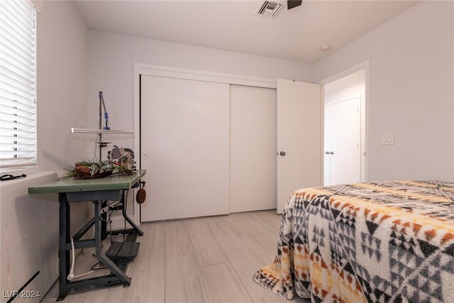 bedroom with a closet, visible vents, and light wood-style flooring