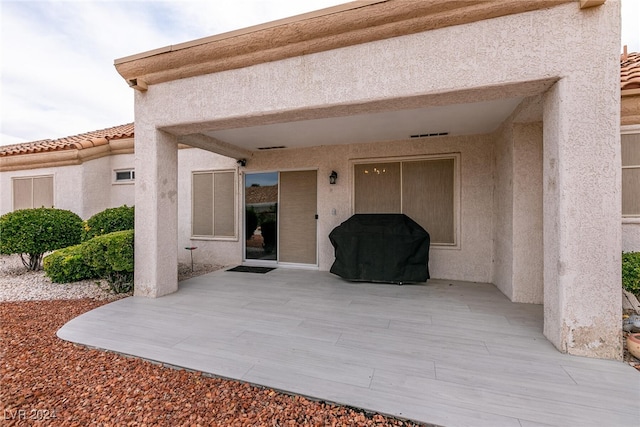 entrance to property featuring a patio, a tiled roof, and stucco siding