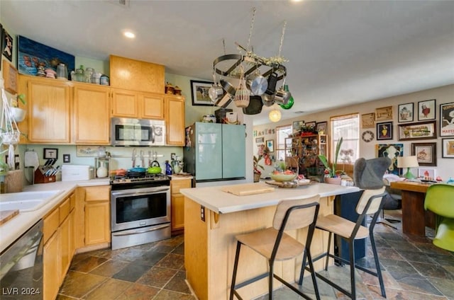 kitchen featuring appliances with stainless steel finishes, a kitchen island, light brown cabinetry, and a breakfast bar area