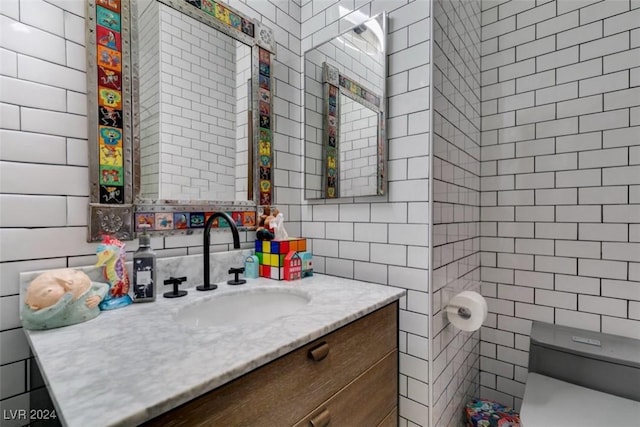 bathroom featuring vanity, tile walls, and toilet