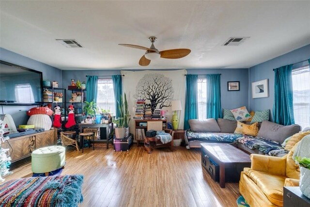 living room with light hardwood / wood-style floors, ceiling fan, and a healthy amount of sunlight