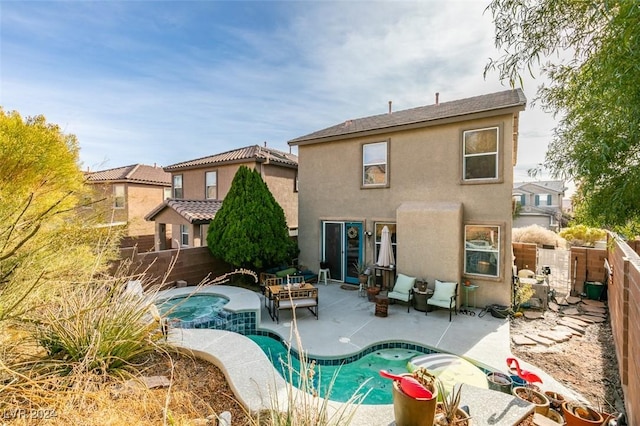 rear view of property featuring a pool with hot tub, a patio area, and an outdoor hangout area