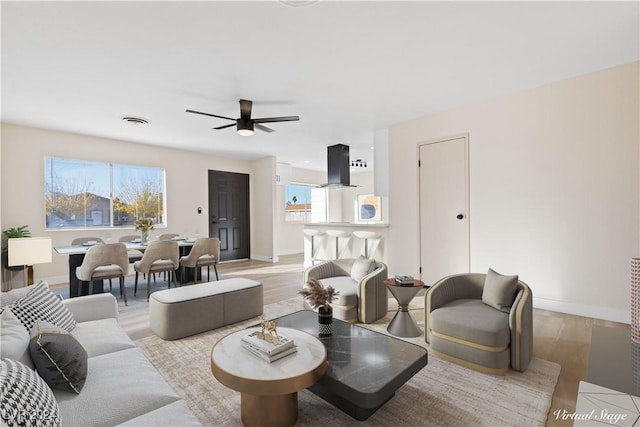 living room featuring light hardwood / wood-style flooring, ceiling fan, and a healthy amount of sunlight