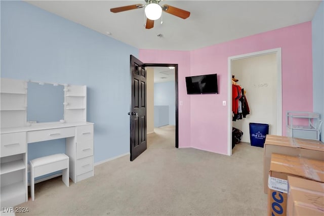 bedroom featuring a walk in closet, ceiling fan, and light colored carpet