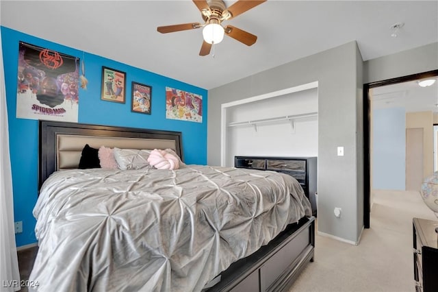 bedroom with ceiling fan, light colored carpet, and a closet