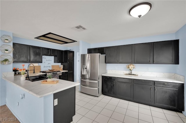 kitchen with light stone countertops, sink, stainless steel appliances, kitchen peninsula, and light tile patterned floors