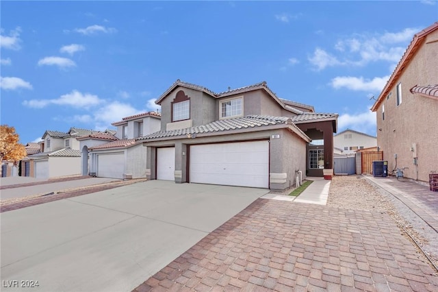 mediterranean / spanish-style house with a garage and central AC unit