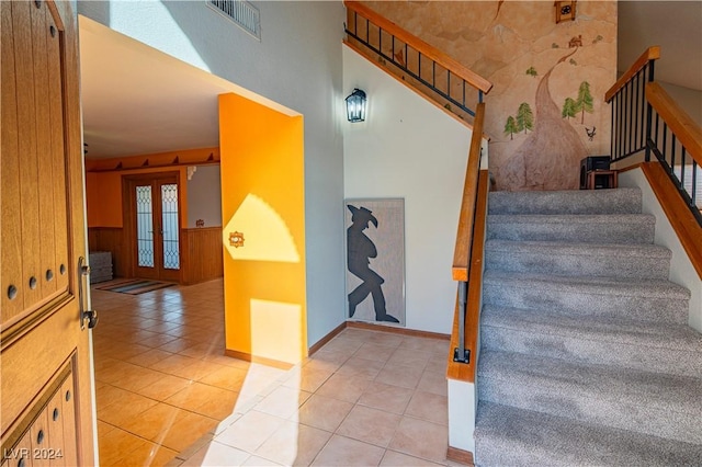 stairs featuring wooden walls, french doors, and tile patterned flooring