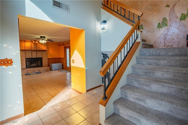 stairs featuring tile patterned flooring, a fireplace, and ceiling fan