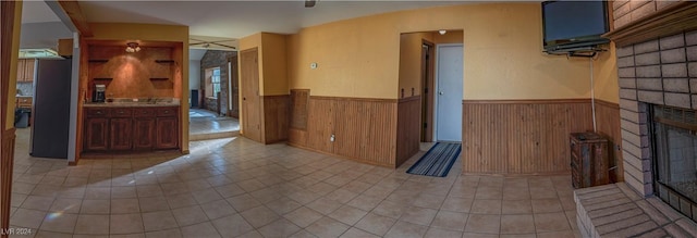 unfurnished living room featuring wood walls, a fireplace, and light tile patterned flooring