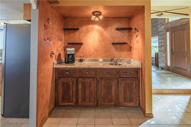 interior space with stainless steel fridge, light tile patterned floors, and sink