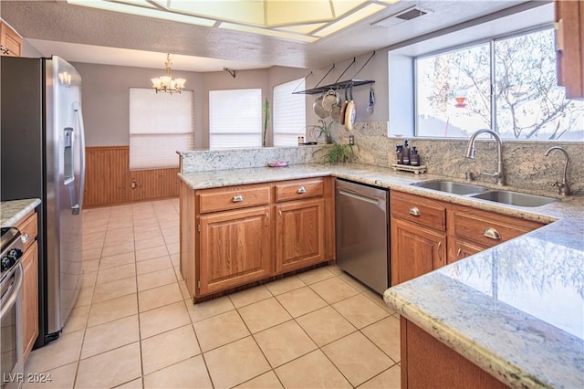 kitchen featuring a healthy amount of sunlight, kitchen peninsula, stainless steel appliances, and hanging light fixtures