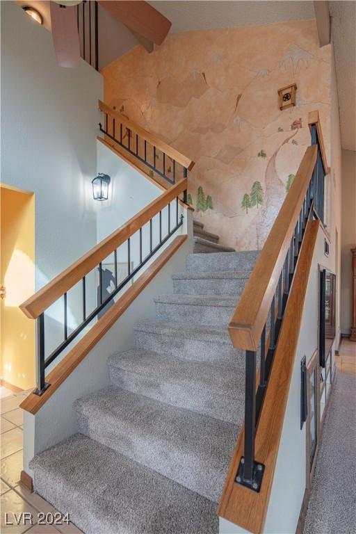 stairway featuring tile patterned flooring and a high ceiling