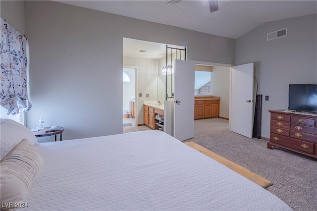 bedroom featuring light carpet, ensuite bath, a textured ceiling, vaulted ceiling, and ceiling fan