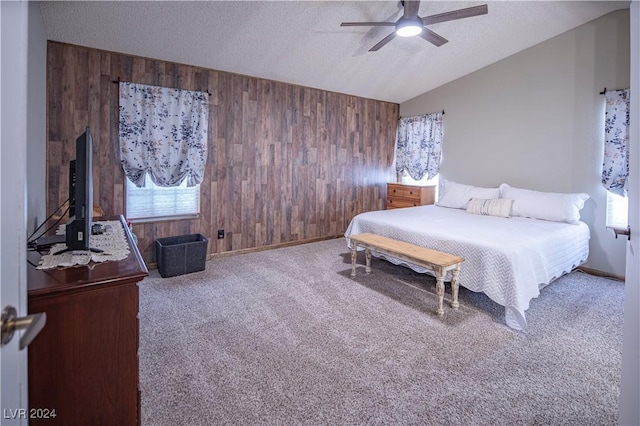 carpeted bedroom featuring ceiling fan, a textured ceiling, wooden walls, and vaulted ceiling