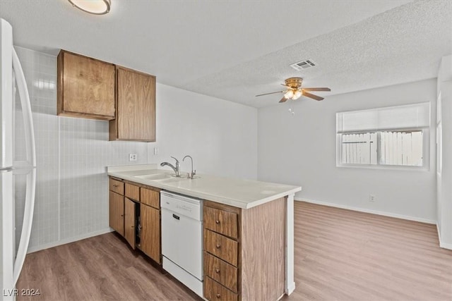 kitchen featuring white appliances, sink, light hardwood / wood-style flooring, ceiling fan, and a textured ceiling