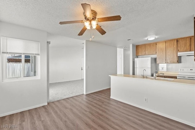 kitchen featuring a textured ceiling, ceiling fan, hardwood / wood-style floors, range, and white fridge