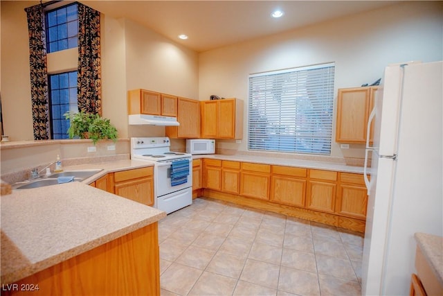 kitchen with under cabinet range hood, light countertops, recessed lighting, white appliances, and a sink