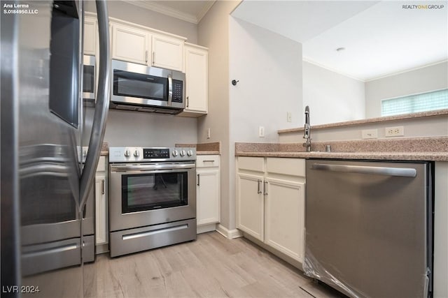 kitchen featuring crown molding, light countertops, stainless steel appliances, light wood-style floors, and white cabinetry