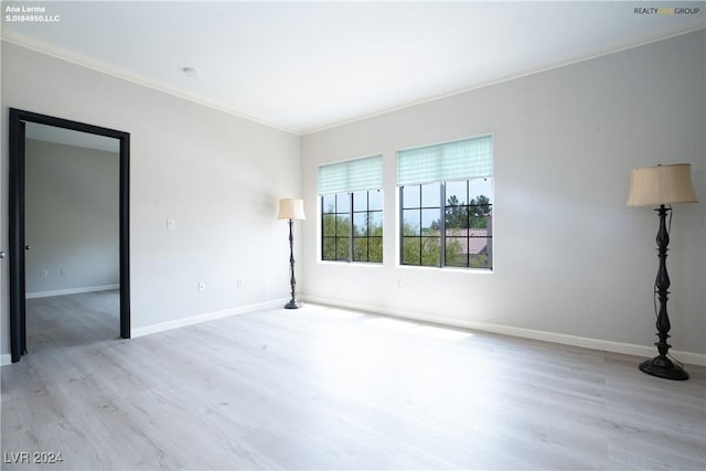 spare room with crown molding, wood finished floors, and baseboards