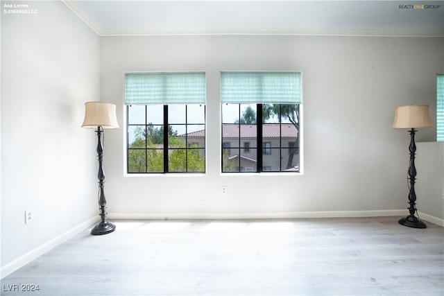 empty room featuring crown molding, wood finished floors, and baseboards