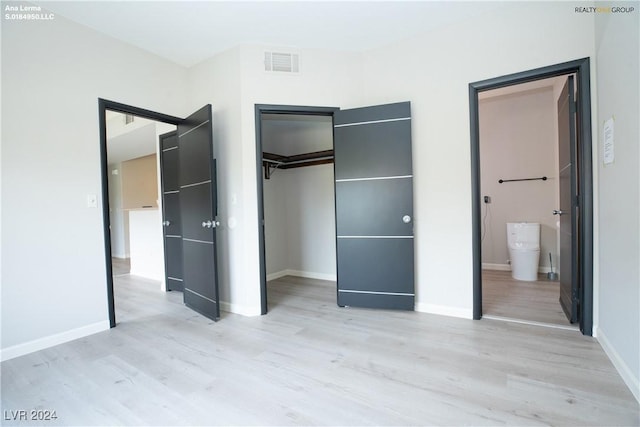 unfurnished bedroom with light wood-type flooring, visible vents, baseboards, and a spacious closet