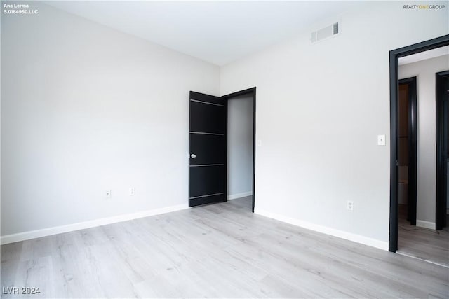 unfurnished bedroom with visible vents, light wood-style flooring, and baseboards