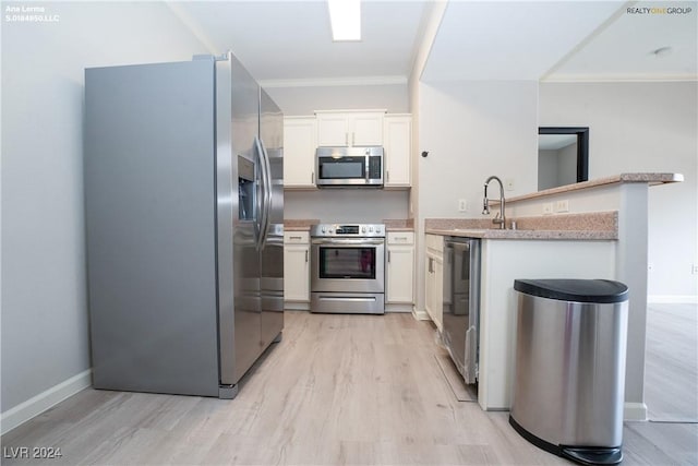 kitchen with a peninsula, light wood-style flooring, light countertops, appliances with stainless steel finishes, and white cabinetry