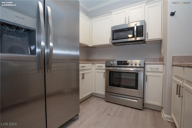 kitchen featuring stainless steel appliances, light wood-style floors, crown molding, and white cabinetry