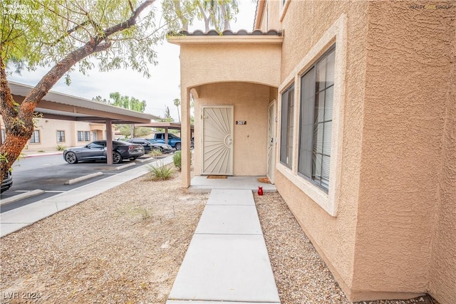 doorway to property with covered and uncovered parking and stucco siding