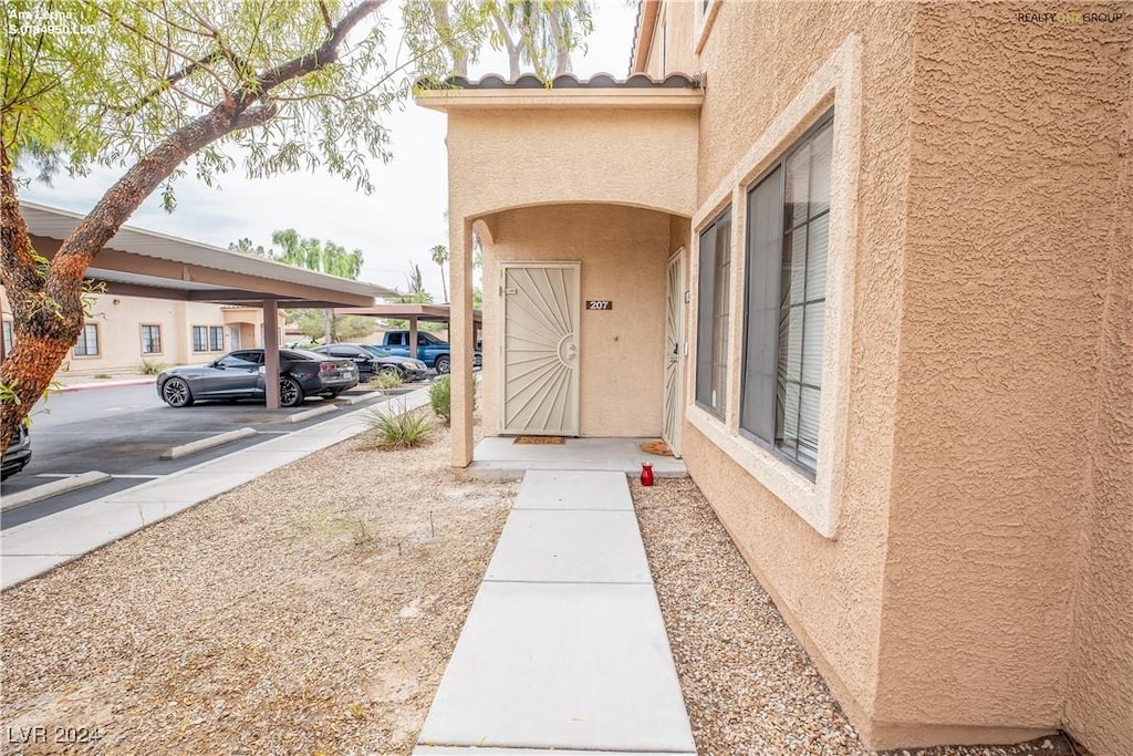 property entrance featuring covered parking and stucco siding