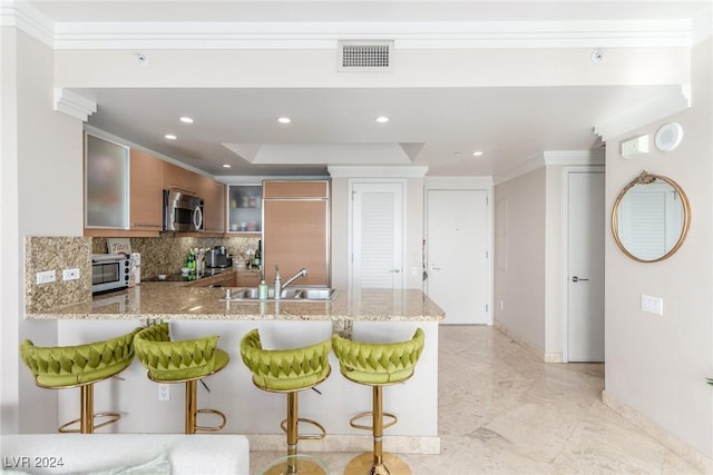 kitchen with light stone countertops, a kitchen breakfast bar, and kitchen peninsula