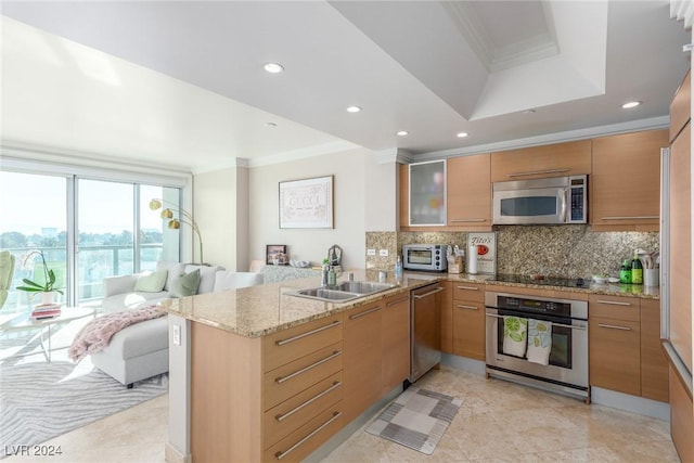 kitchen with sink, appliances with stainless steel finishes, a tray ceiling, ornamental molding, and kitchen peninsula