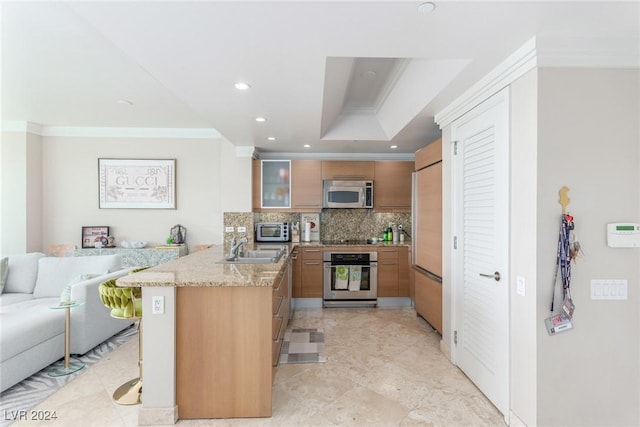 kitchen featuring a breakfast bar area, appliances with stainless steel finishes, light stone countertops, ornamental molding, and kitchen peninsula