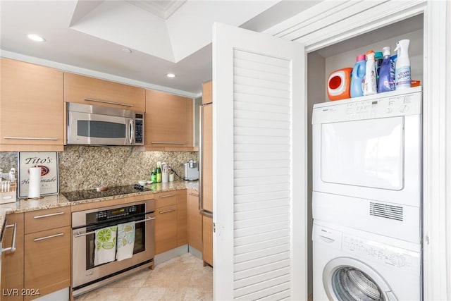 kitchen with light tile patterned flooring, stacked washer and dryer, tasteful backsplash, light stone counters, and stainless steel appliances