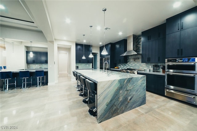 kitchen with a spacious island, wall chimney exhaust hood, a kitchen bar, and hanging light fixtures