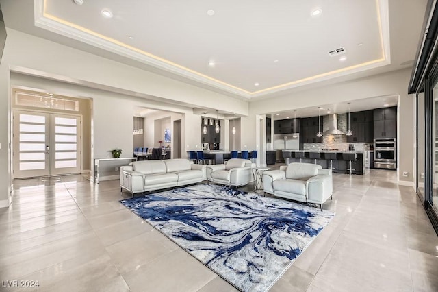 tiled living room featuring french doors and a tray ceiling