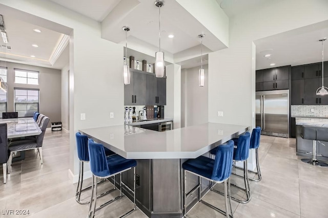 kitchen with a breakfast bar, built in refrigerator, decorative backsplash, decorative light fixtures, and kitchen peninsula