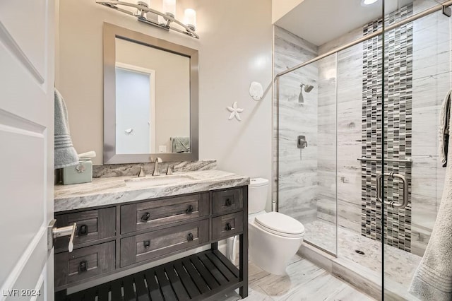 bathroom with a shower with door, vanity, and toilet