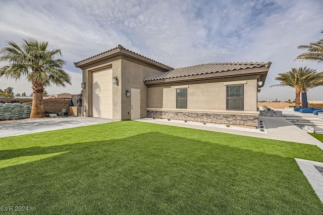 back of property featuring a garage and a lawn