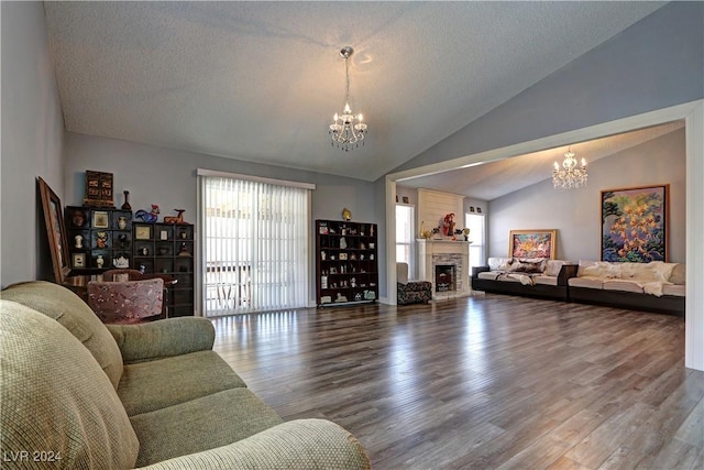 living room featuring hardwood / wood-style floors, lofted ceiling, a textured ceiling, a fireplace, and a chandelier