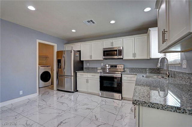 kitchen with stainless steel appliances, white cabinetry, washer / clothes dryer, and sink