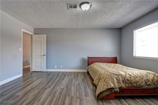 bedroom with hardwood / wood-style flooring and a textured ceiling